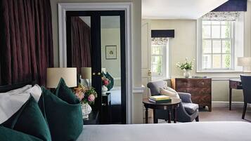 A hotel room with a bed, a desk, a chair, a dresser, and a door leading to another room.