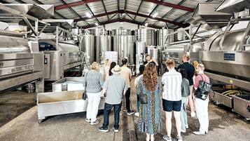 A group of people in a large industrial facility with stainless steel tanks and machinery.