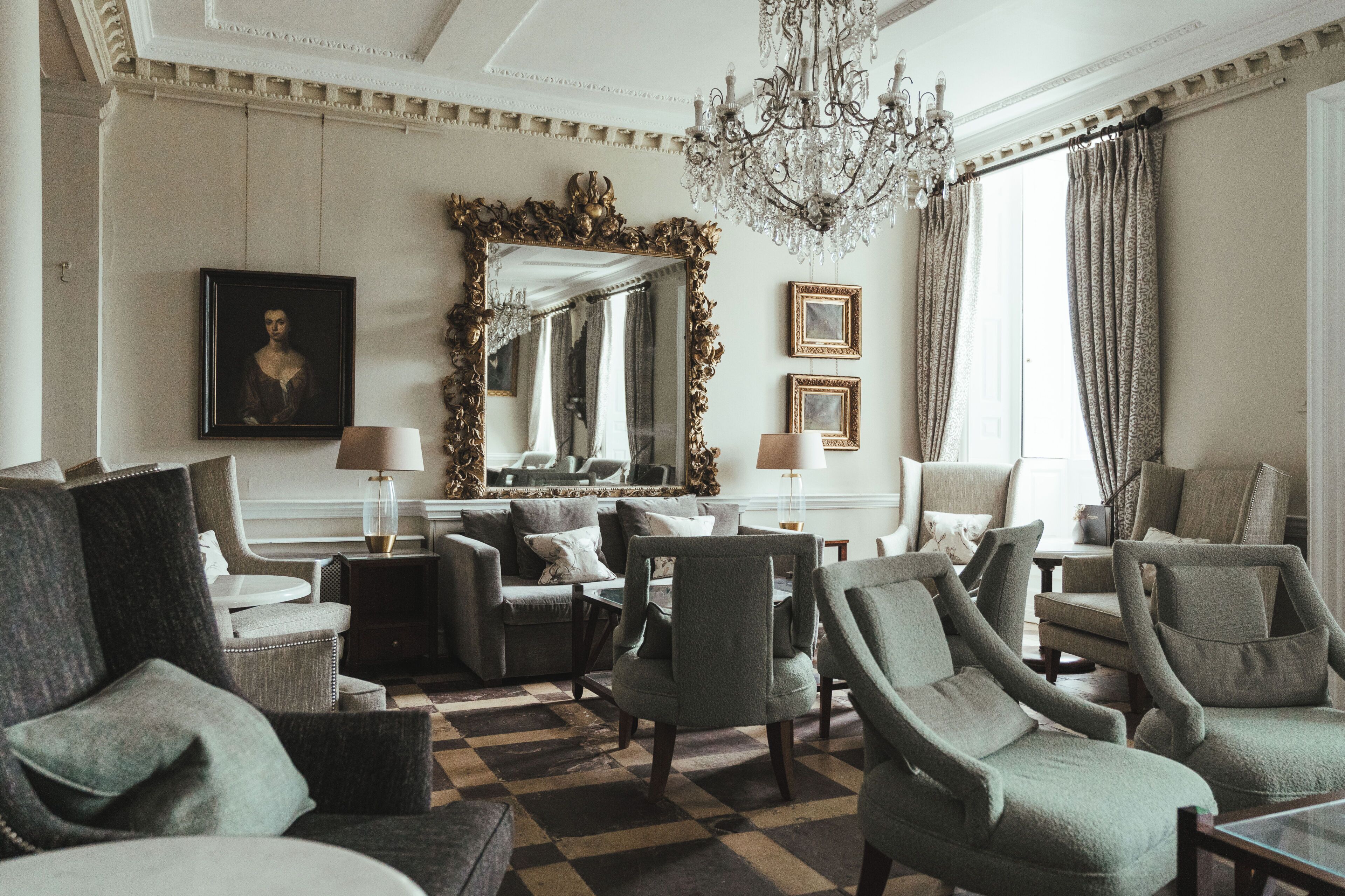 Un interior clásico con suelo a cuadros, muebles elegantes y un espejo grande y ornamentado.