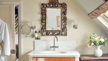 A bathroom with a white sink, ornate gold-framed mirror, and a wooden cabinet.