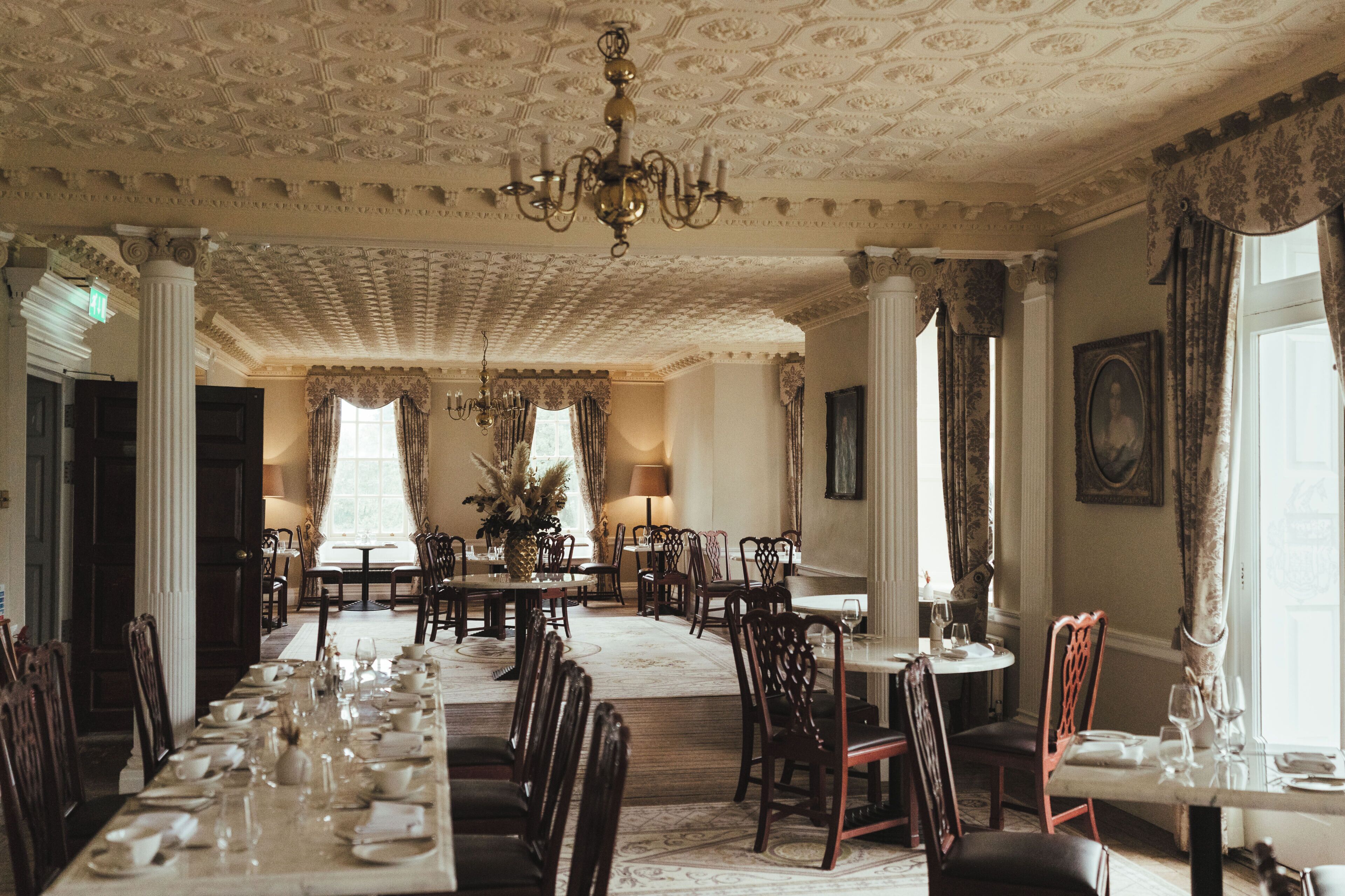 A formal dining room with a long table set for a meal, surrounded by chairs.