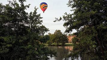 A hot air balloon over a body of water surrounded by trees.