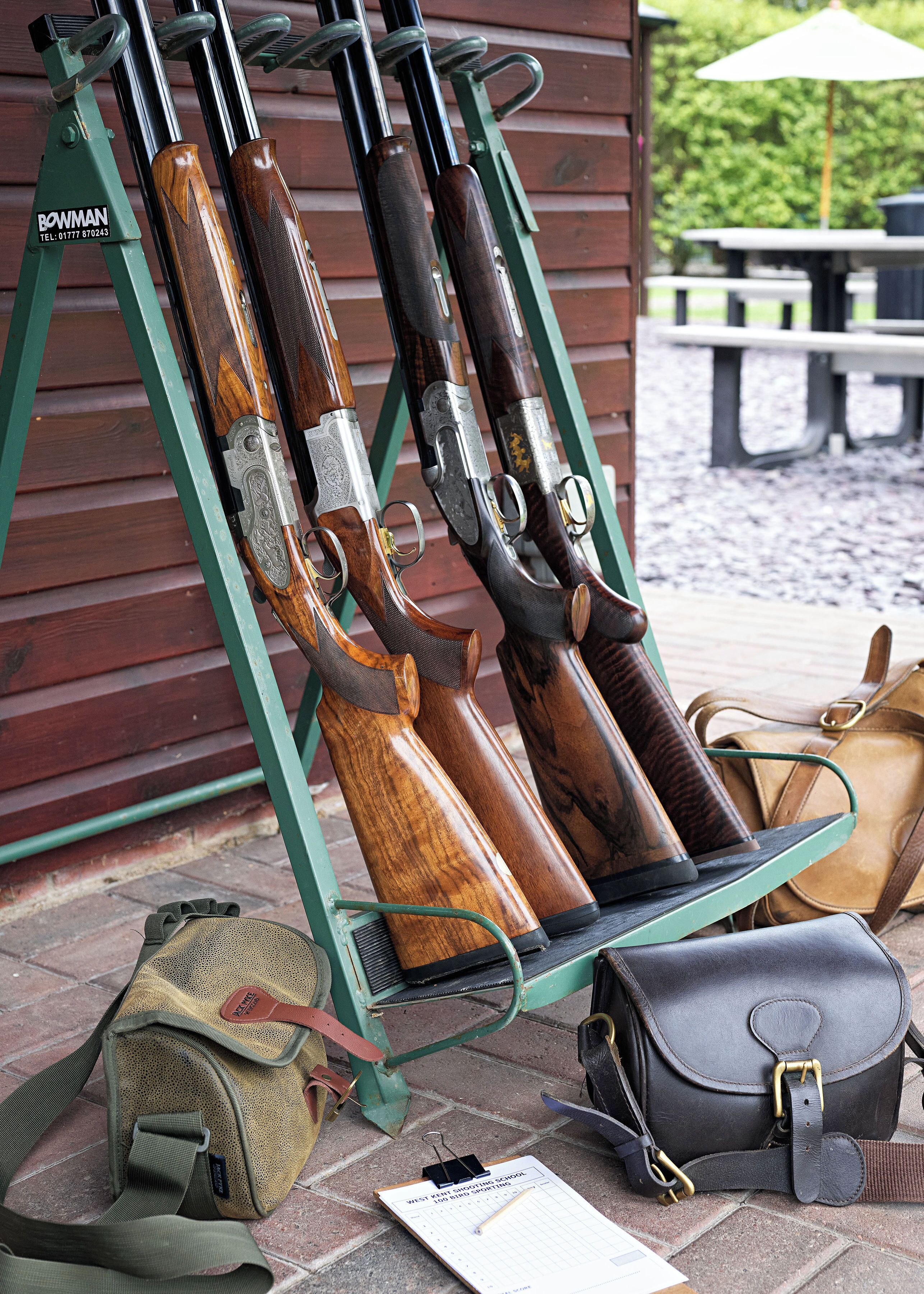 A wooden structure with rifles mounted on it, a bench, and a table with a canopy.