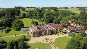 Explore a historic estate with a traditional main building, outbuildings, and a gazebo amidst beautifully manicured grounds.