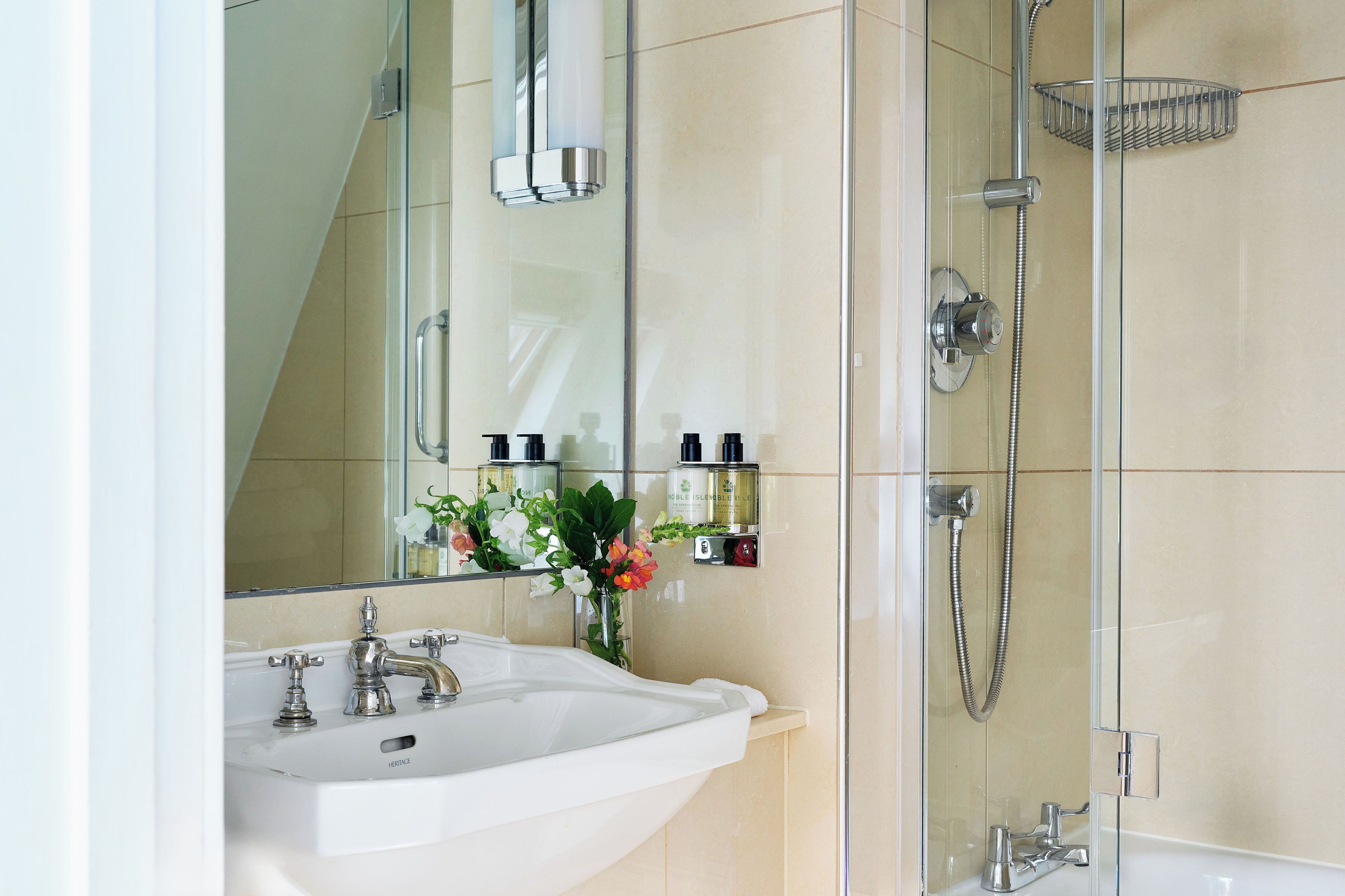 A bathroom with a white sink, a mirror, a shower, and a towel rack.