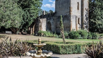 Una torre de piedra histórica con un jardín en primer plano.
