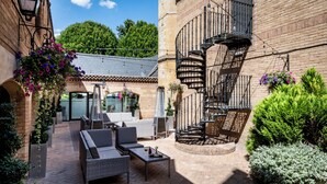 Un patio con mobiliario exterior, una escalera de caracol y un edificio de ladrillo.
