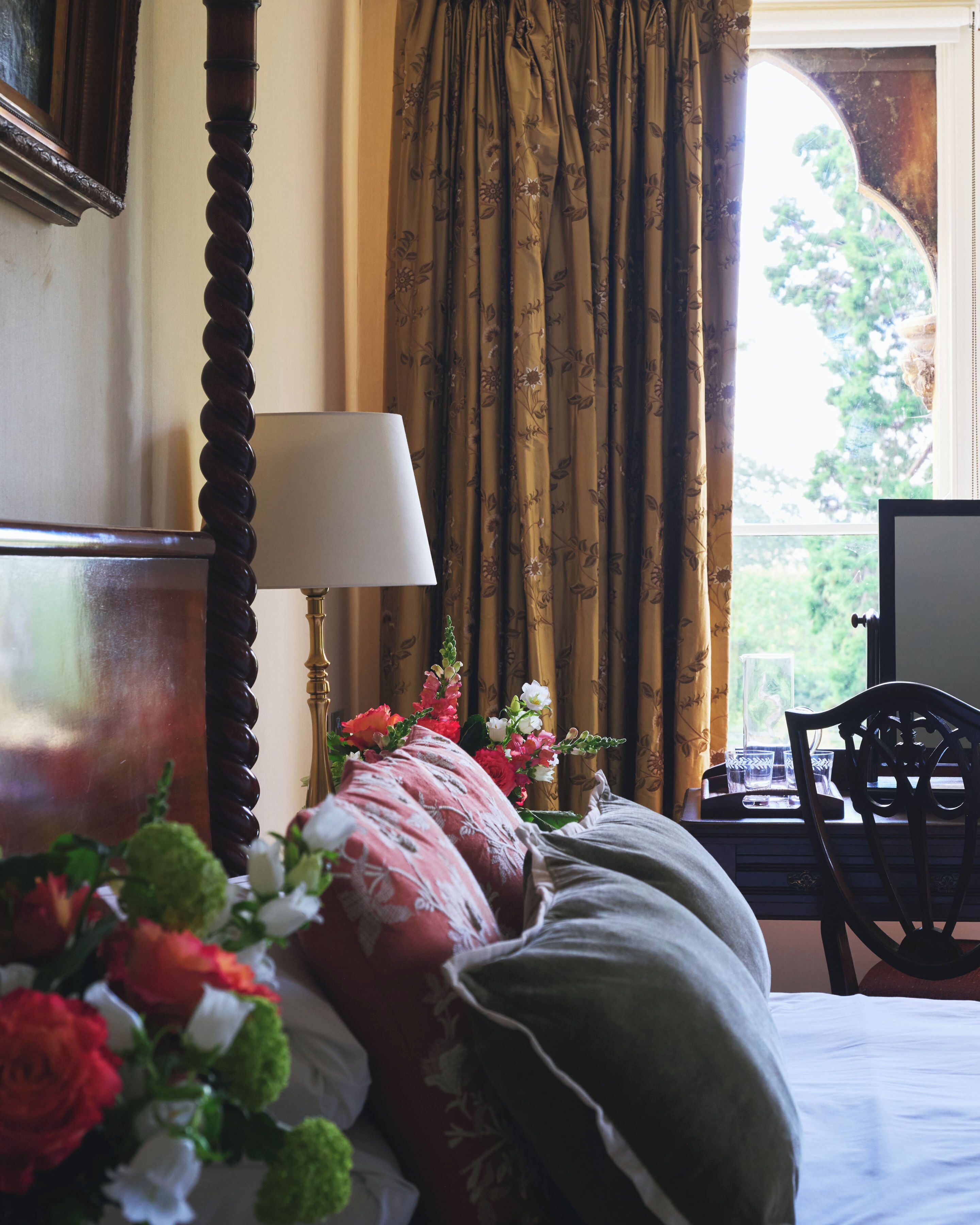 Habitación de hotel con cama, lámpara, silla y ventana con cortinas.