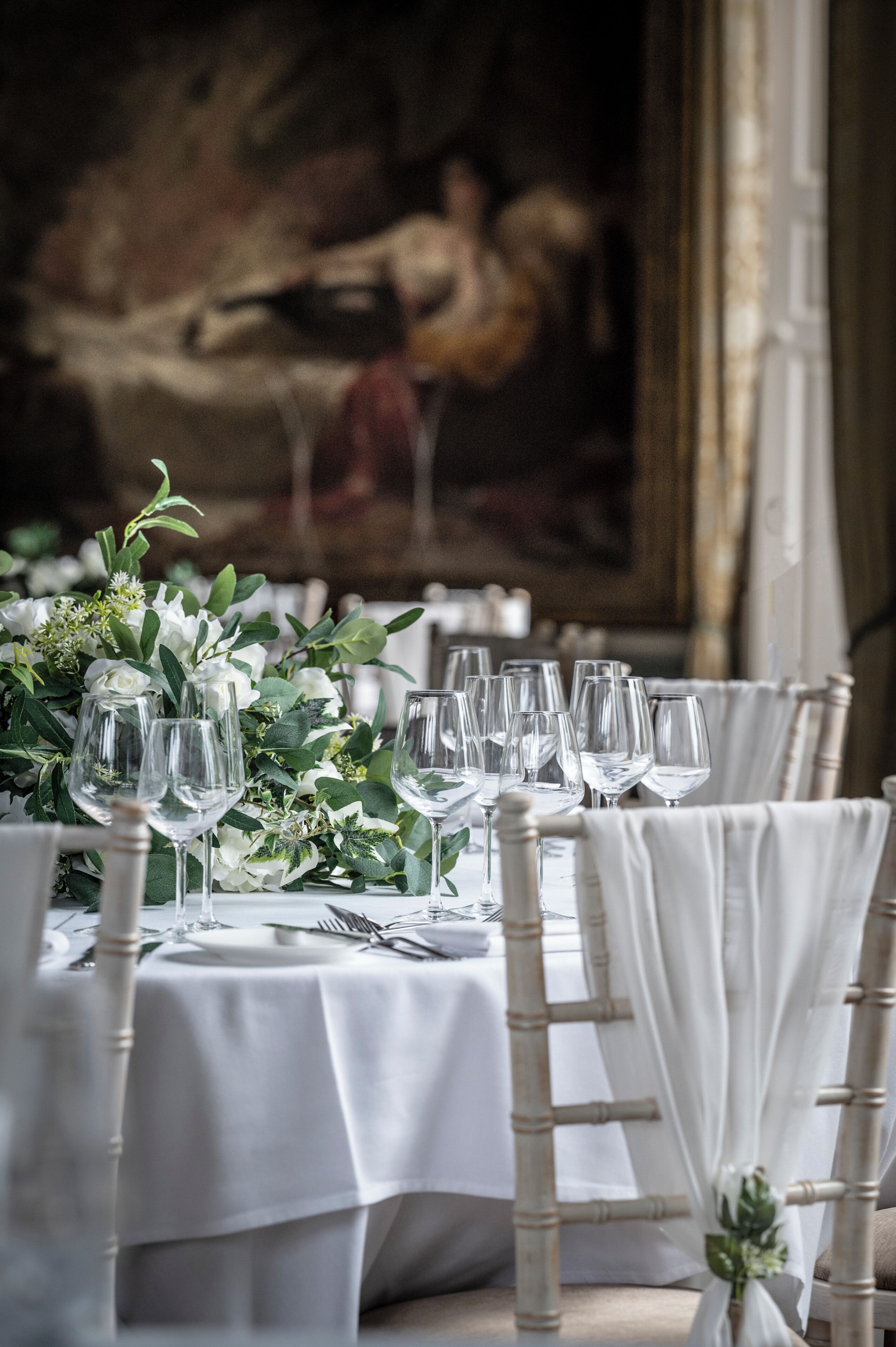 A table set for dining with white tablecloths, clear glassware, and a floral centerpiece.