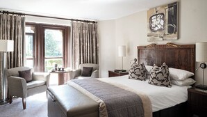 Habitación de hotel con una cama grande, dos sillones, una mesita y vistas al exterior.