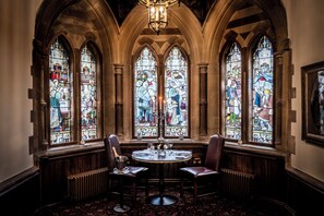A dining area with a round table, two chairs, and a chandelier. - Ettington Park Hotel (Stratford-upon-Avon)