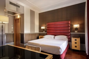 A hotel room with a large bed, bedside tables, a desk, and a chair.