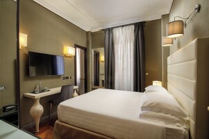 A hotel room with a bed, a desk, a television, and a mirror.