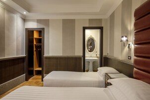 A hotel room with two beds, a mirror, a sink, and a wardrobe.
