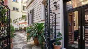 A courtyard with a tiled floor, potted plants, and a wrought iron gate. - Hotel Royal Court (Rome)