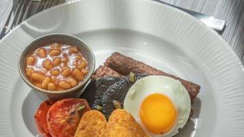 A plate with a steak, fried egg, beans, and tomato slices.