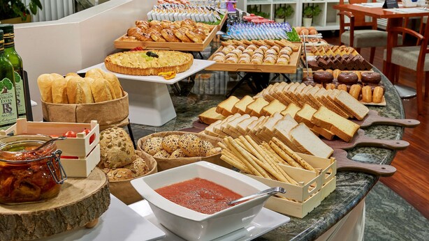 Un buffet con diversi tipi di pane, pasticcini e una ciotola di salsa rossa.