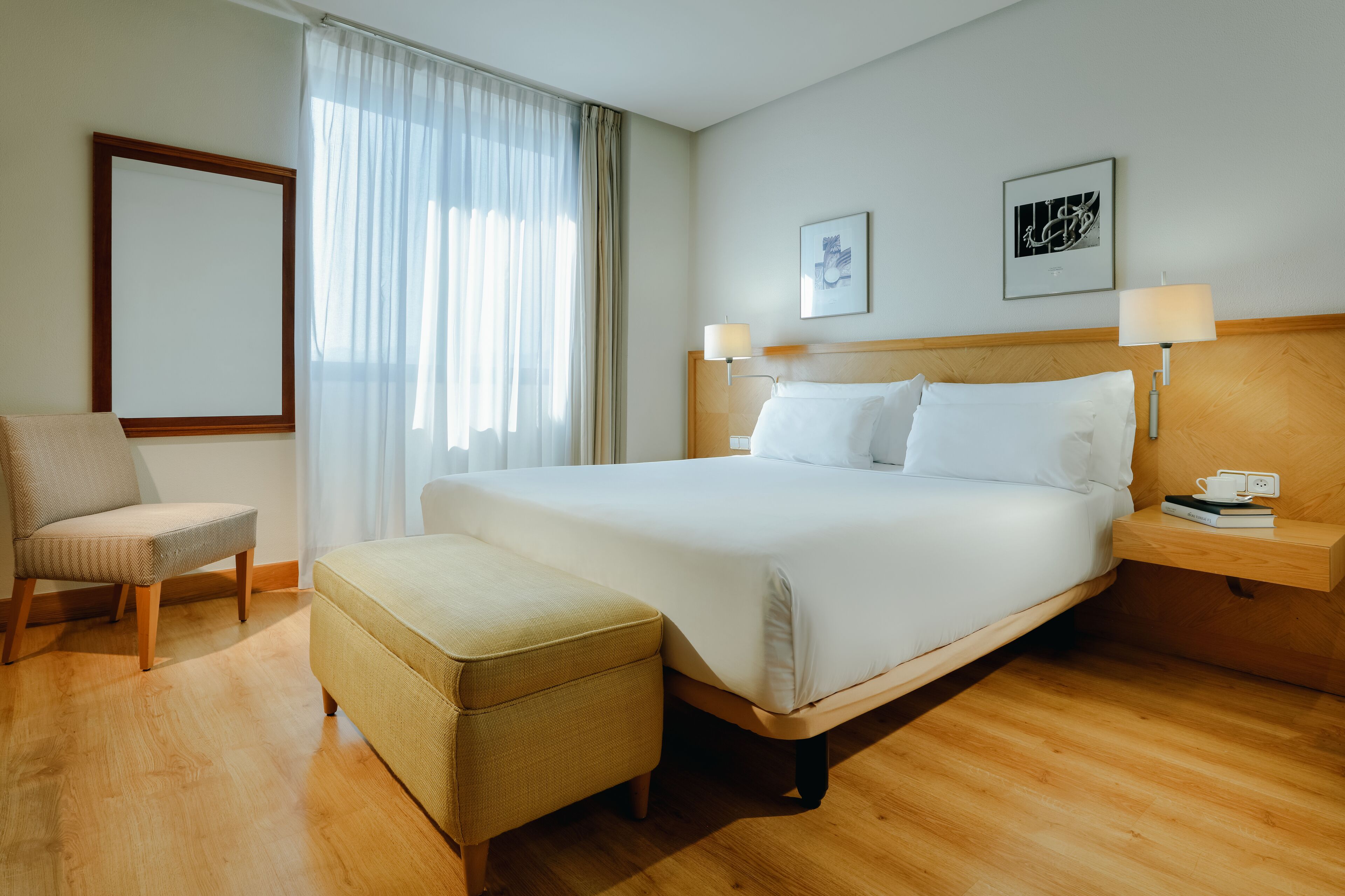 A hotel room with a bed, a chair, a small table, and a nightstand.
