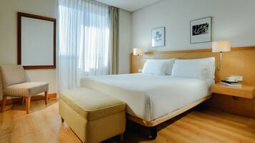 A hotel room with a bed, a chair, a small table, and a nightstand.