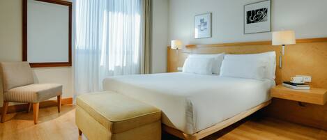 A hotel room with a bed, a chair, a small table, and a nightstand.