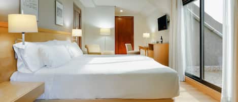 Una camera d'albergo con un letto grande, comodini, una scrivania, una sedia e un'ampia finestra con tende.