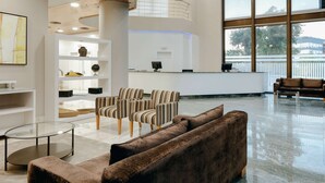Un'ampia hall con una reception, sedie a righe, un divano marrone e un tavolino da caffè in vetro.