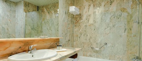 A bathroom with a marble sink, a glass-enclosed shower, and a bathtub.