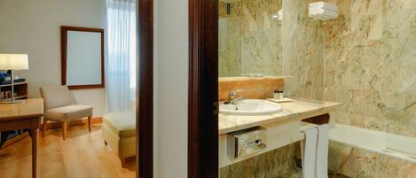 A modern hotel bathroom with a marble sink, a bathtub, and a shower.