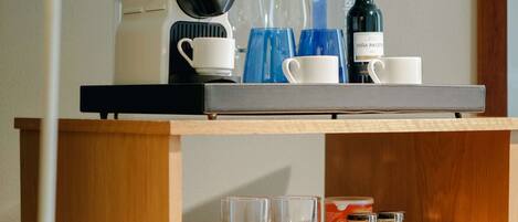 A neatly organized table with a lamp, a kettle, cups, and bottles, suggesting a self-service breakfast area in a hotel.