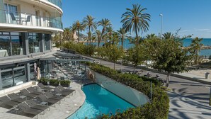 A poolside area with lounge chairs, a pool, and a view of the sea. - Hotel Calipolis (Sitges)