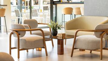 Un interior moderno con una mesa de centro de vidrio, sillas tapizadas en tono beige y una planta en maceta.