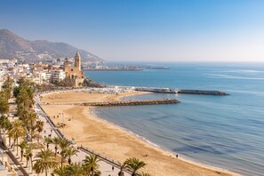 A coastal cityscape with a prominent church, a sandy beach, and a calm sea.