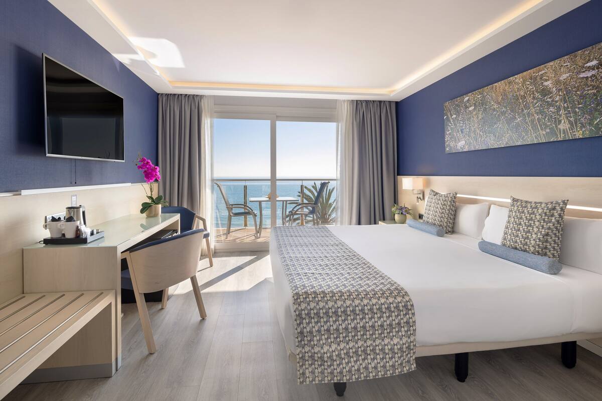 A modern hotel room with a large bed, a desk, and a TV.