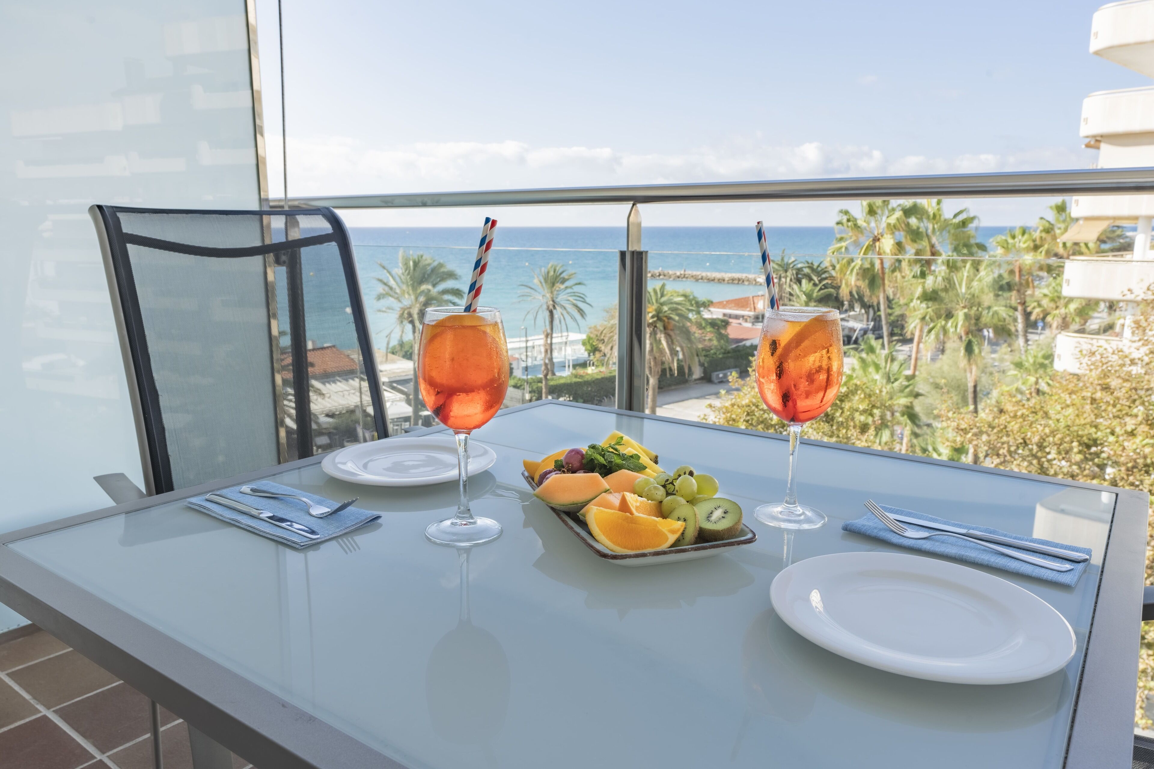 A dining table with a fruit platter, two glasses of orange beverage, and a white plate.