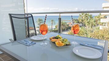 A dining table with a fruit platter, two glasses of orange beverage, and a white plate.