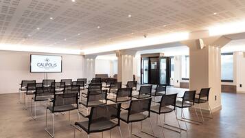 A conference room with rows of chairs and a screen displaying the hotel name.