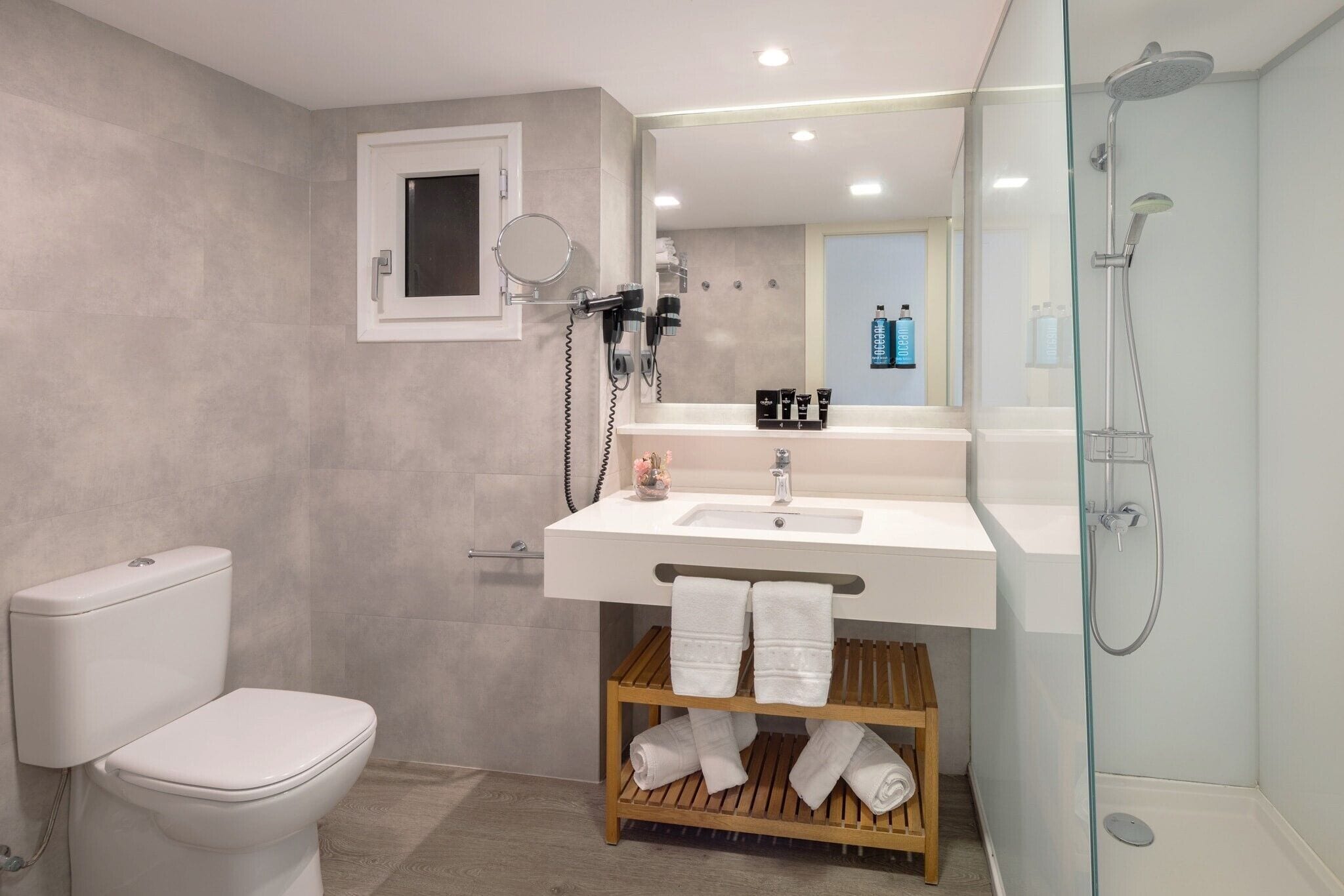 Une salle de bain moderne équipée de toilettes, d’un lavabo et d’une douche à parois de verre.