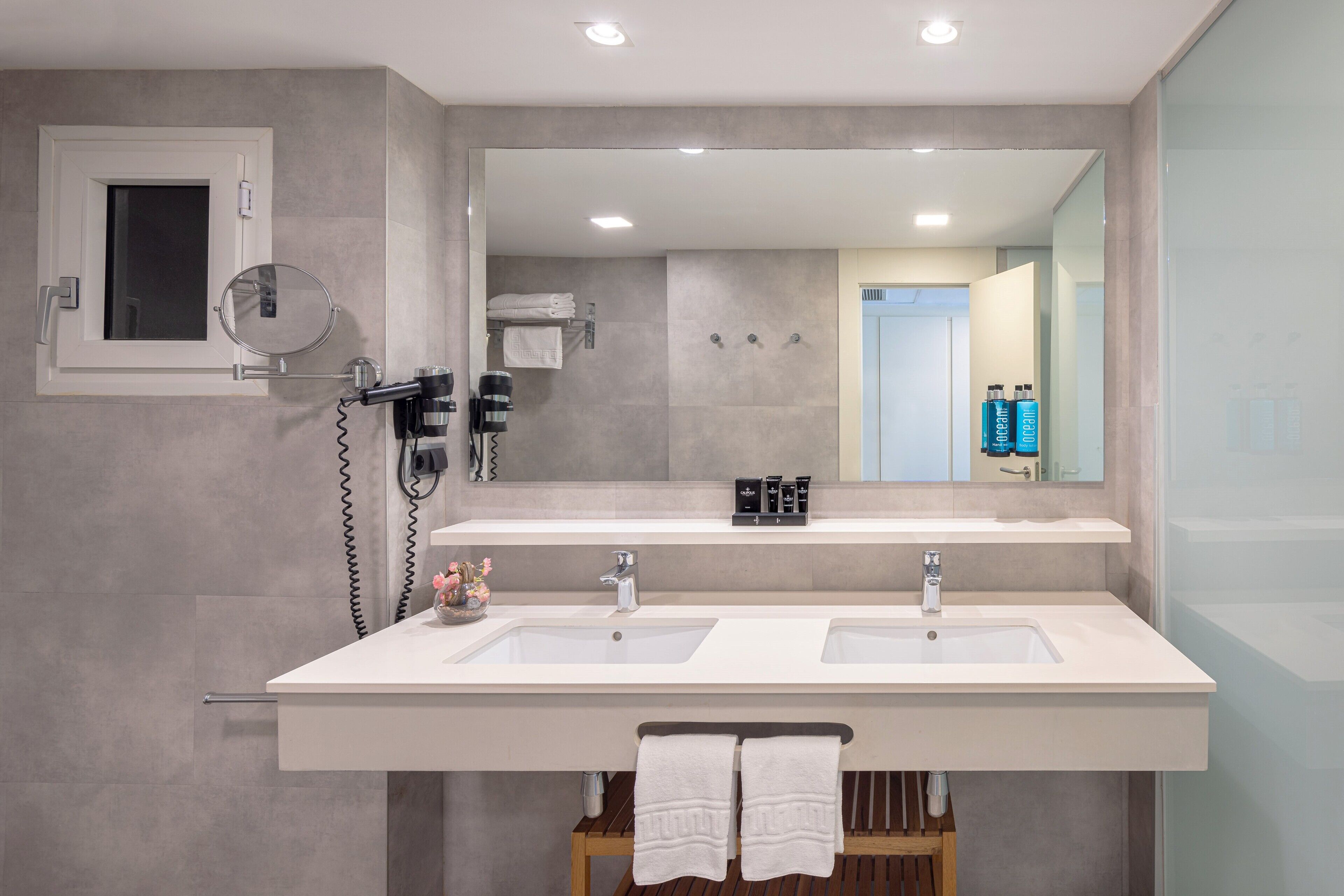 Un baño moderno con dos lavamanos, un espejo grande y un secador de pelo.