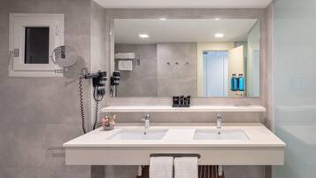 Un baño moderno con dos lavamanos, un espejo grande y un secador de pelo.