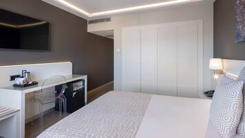 Una habitación de hotel moderna con una cama, un escritorio con una silla, un televisor y un armario.