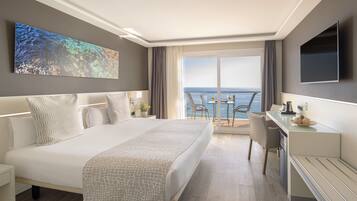 Habitación de hotel moderna con una cama grande, un escritorio y un balcón con vista al mar.