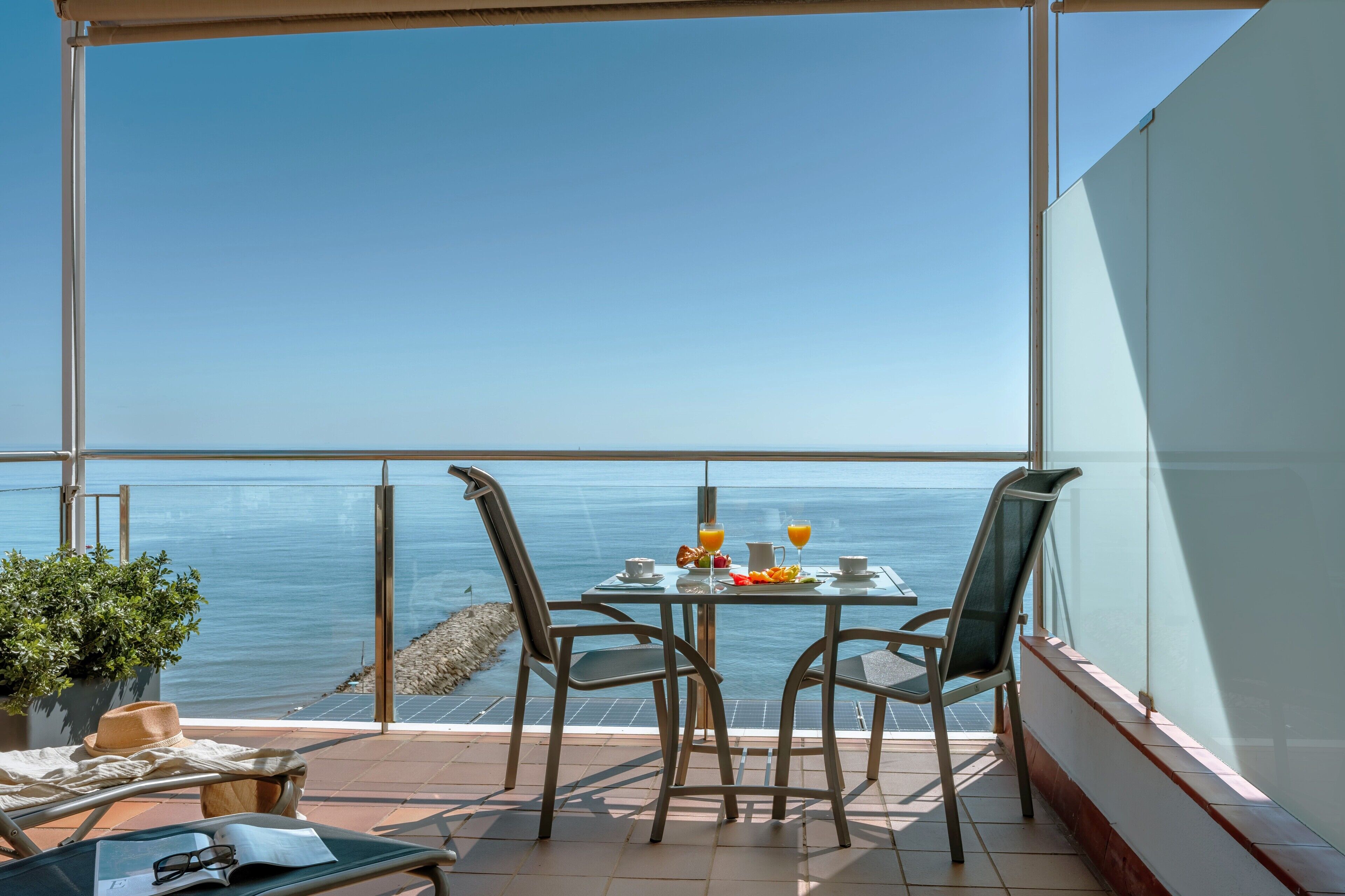 A balcony with a table set for two, overlooking a body of water.
