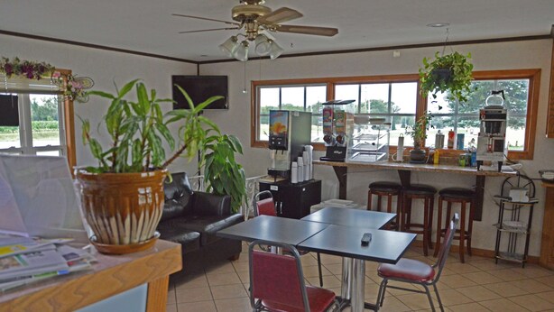 A dining area with a table, chairs, a coffee machine, and a potted plant. - Americas Best Value Inn Suburban Motel (Emmetsburg)