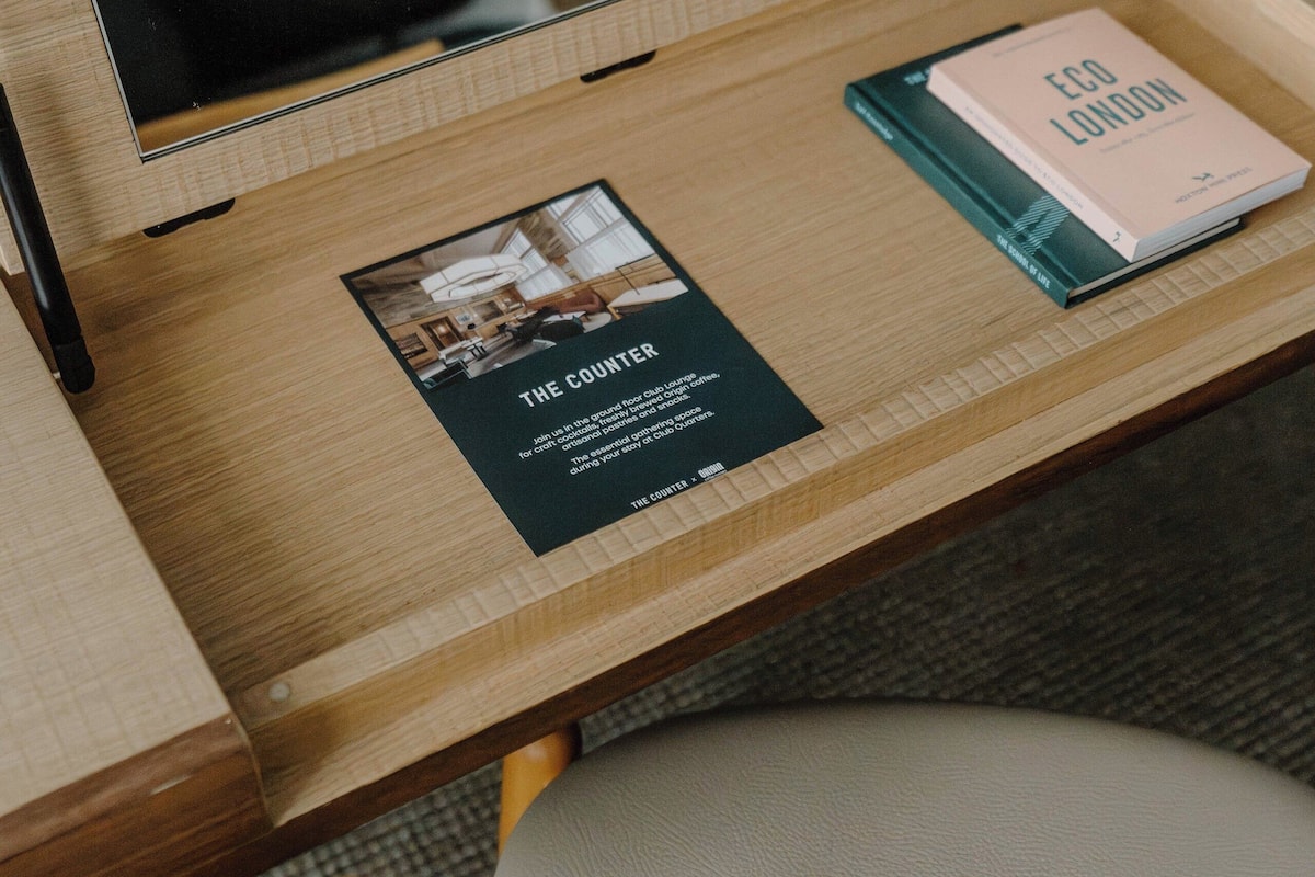 A wooden desk with a mirror, a book titled 'Eco London', and a pamphlet.
