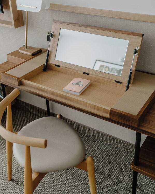 A wooden desk with a mirror, a book titled 'Eco London', and a chair.