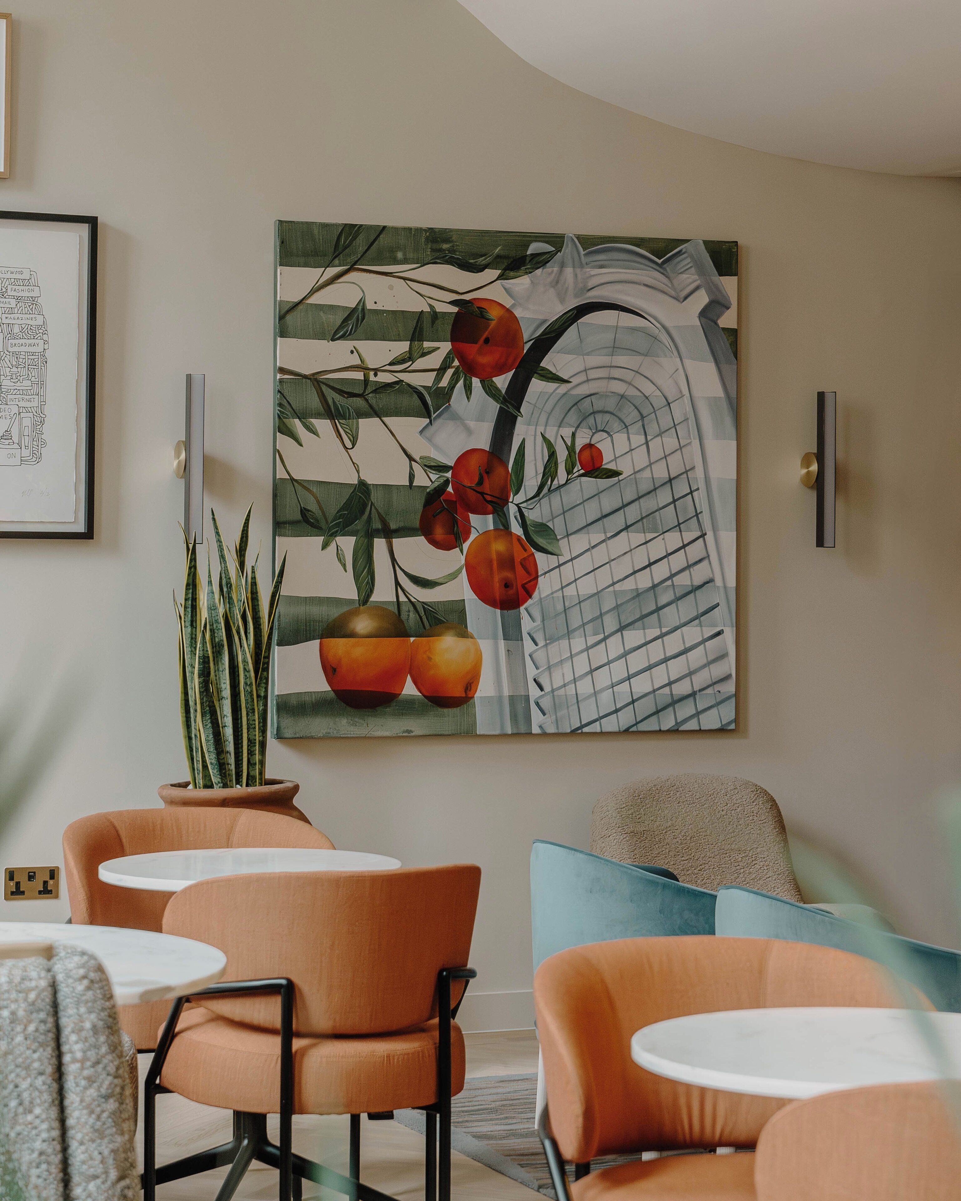 A modern living room with orange and blue furniture, a large fruit painting, and a potted plant.