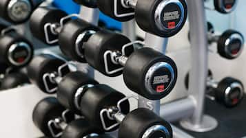 A rack of black dumbbells with weight labels, including 16kg and 44kg options, mounted on a metal frame.