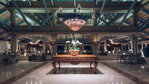 A spacious lobby with a large ornate table, a chandelier, and horse statues.