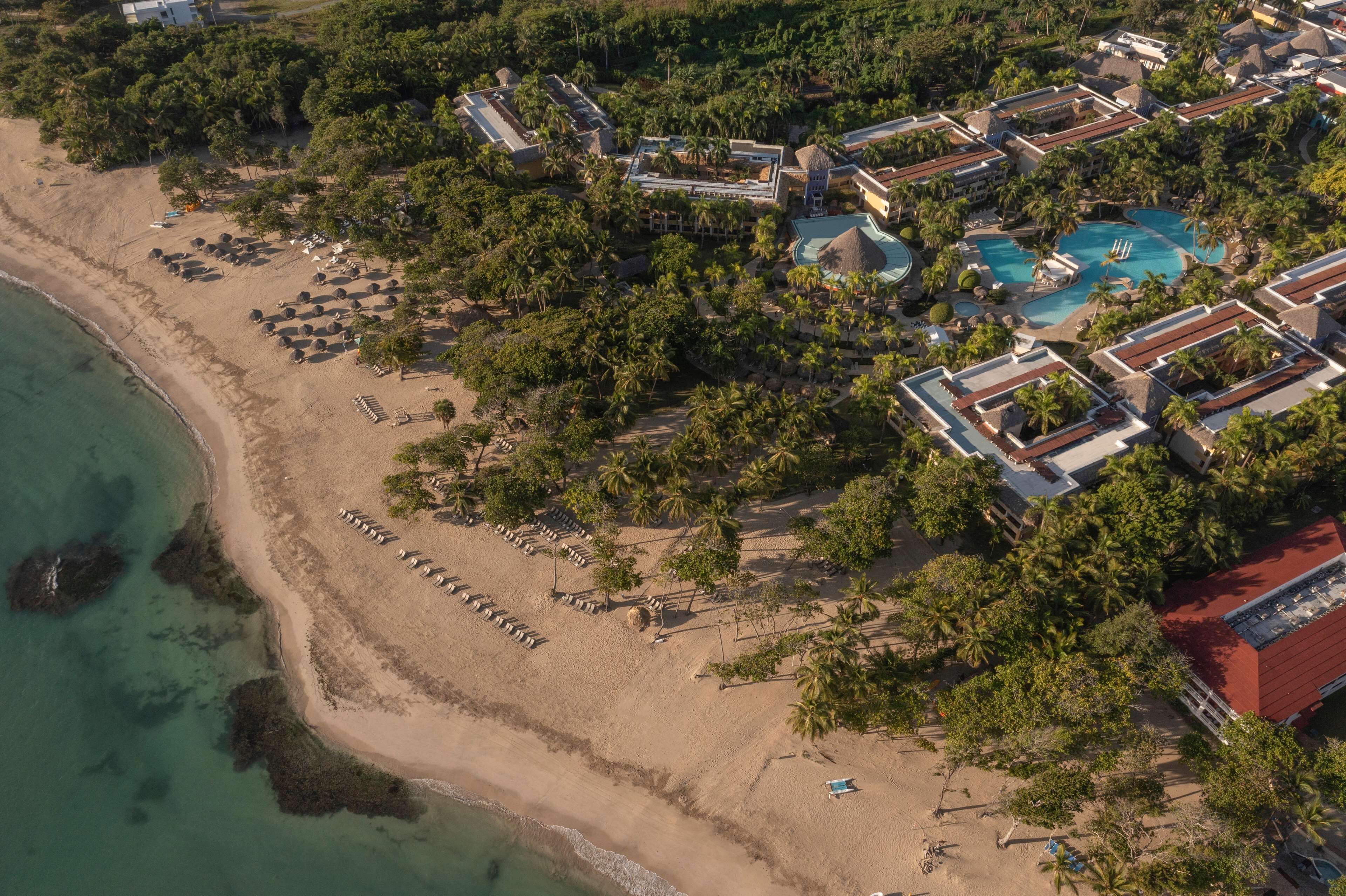 An aerial view of a resort with a beach, pool, and multiple buildings.