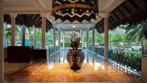 A lobby with a marble floor, a large decorative vase, and a thatched roof.